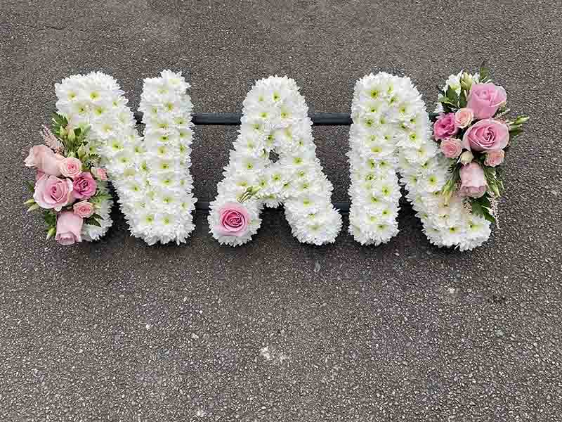 White and pink lettering for a funeral that spells out nan in flowers