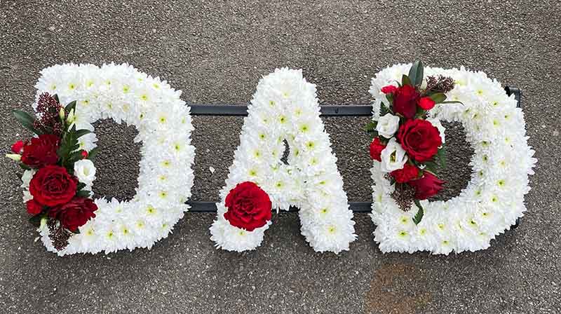 White and red funeral flower writing spelling out dad
